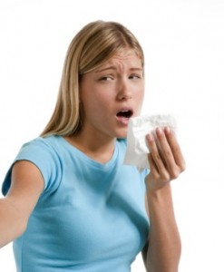 Young woman blowing her nose. Flowers representing seasonal allergens.